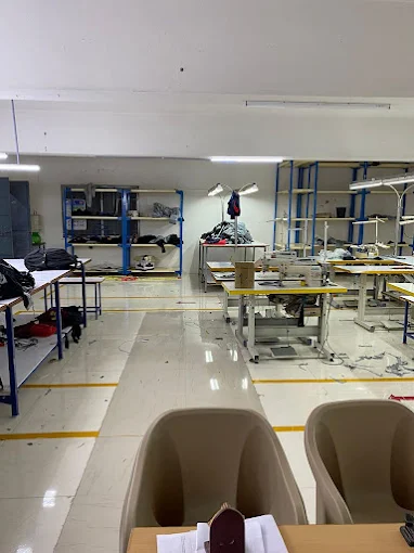 Another view of the SK GARMENTS workshop, showing worktables, machines and fabric storage
